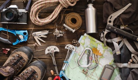 Equipment necessary for mountaineering and hiking on wooden background
